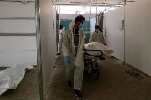 عاملون في مجال الطب يحملون جثة فلسطيني في مرفق طبي، وسط آثار تعذيب على بعض الجثث، في سياق إعادة الجثامين إلى غزة.
