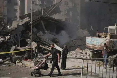 مشهد من الضاحية الجنوبية لبيروت يظهر دمارًا واسعًا بعد غارات إسرائيلية، مع شخص يدفع عربة طفل وسكان يتنقلون في المنطقة.