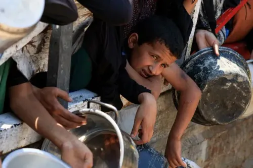طفل فلسطيني يعبر عن معاناته أثناء انتظار المساعدات الغذائية في غزة، وسط أزمة إنسانية متفاقمة وسوء التغذية.