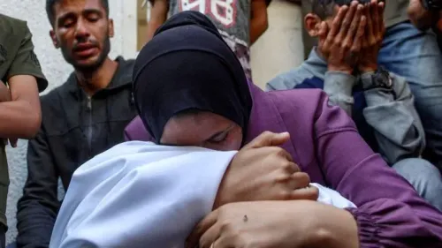 امرأة تحتضن طفلاً، بينما يظهر في الخلفية رجال يظهر عليهم الحزن، في سياق الهجمات الإسرائيلية على غزة التي أودت بحياة العديد من الفلسطينيين.