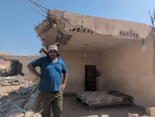 رجل فلسطيني يقف في غرفة مهدمة جزئياً بمنزل في حي الستيح بأريحا، يعكس آثار الهجمات الاستيطانية والهدم المستمر.