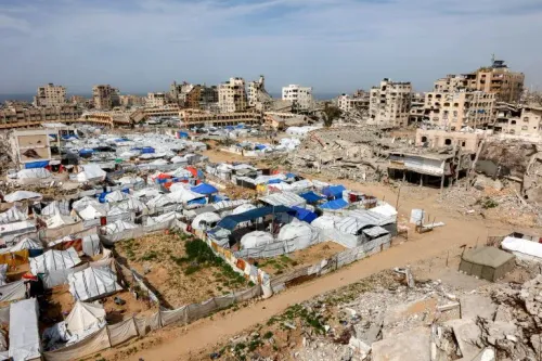 تظهر الصورة مشهدًا من مدينة غزة بعد القصف، حيث تتواجد خيام مؤقتة للنازحين وسط المباني المدمرة، مما يعكس الأثر الدمار على المدنيين.
