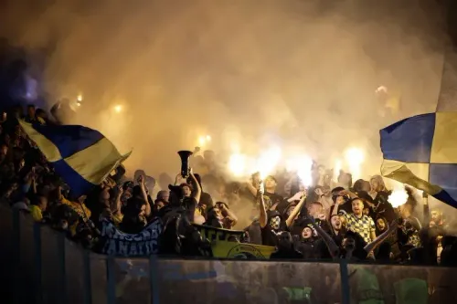 مشجعو مكابي تل أبيب يحتفلون في الملعب، يحملون الأعلام ويضيئون الشماريخ وسط أجواء مشحونة، تعبيرًا عن دعمهم للفريق.