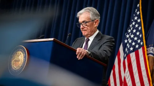 جيروم باول، رئيس الاحتياطي الفيدرالي، يتحدث خلال مؤتمر صحفي، مع العلم الأمريكي خلفه، معبرًا عن القلق بشأن التضخم والنمو الاقتصادي.
