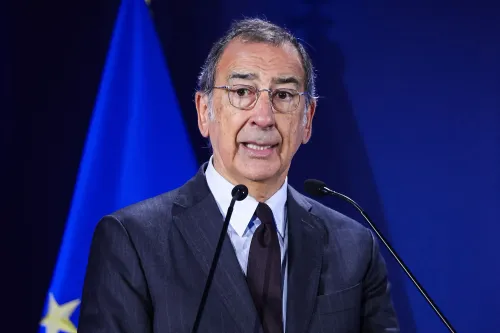 رجل يتحدث في مؤتمر صحفي مع العلم الإيطالي خلفه، يناقش وجود عملاء إدارة الهجرة والجمارك الأمريكية في أولمبياد ميلانو.