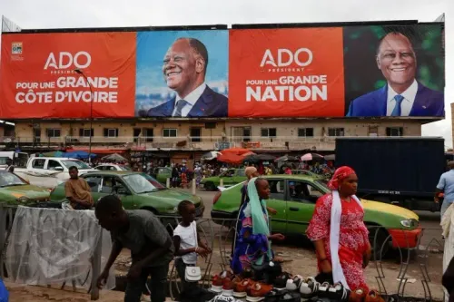 لافتة انتخابية كبيرة تظهر صورة الرئيس الحسن واتارا مع عبارة "من أجل كوت ديفوار عظيمة" في وسط مدينة أبيدجان، مع وجود أشخاص ومركبات في الخلفية.
