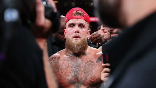 جيك بول، مصمم اليوتيوب والملاكم، يظهر بعد نزال مثير، مع تعبيرات تدل على التوتر والتحدي، محاطاً بجمهور متحمس.