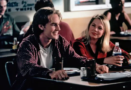 مشهد من مسلسل "داوسونز كريك" يظهر جيمس فان دير بيك وممثلة أخرى في مقهى، يعكسان أجواء المراهقة والعلاقات في التسعينيات.