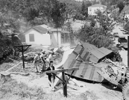 تظهر الصورة عمالًا في موقع إخلاء تشافيز رافين، حيث تُهدم المنازل في الخمسينيات، مما يعكس تأثير التقدم العمراني في لوس أنجلوس.