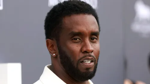 صورة مقربة لرجل ذو لحية قصيرة وشعر مجعد، يبدو وكأنه يتحدث بجدية، مما يعكس التوترات المرتبطة بمحاكمته.