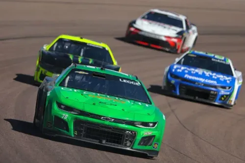 سيارة سباق خضراء تقودها كاثرين ليج تتنافس في سباق ناسكار، مع سيارات أخرى في الخلفية، تعكس روح التحدي في رياضة السيارات.