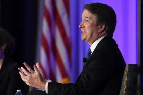 القاضي بريت كافانو يتحدث خلال حدث، مع العلم الأمريكي في الخلفية، حول قضايا حقوق الإنسان والهجرة.