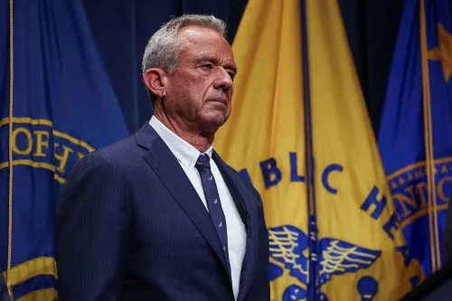 وزير الصحة الأمريكي روبرت كينيدي جونيور يقف أمام الأعلام الرسمية، معبراً عن خططه لإصلاح برنامج تعويض إصابات اللقاحات.