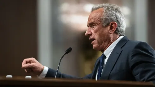 شخص يتحدث في جلسة استماع، مع التركيز على تعبيرات وجهه وحركات يده، في سياق مناقشة حول تفشي مرض الحصبة والعلاجات المقترحة.