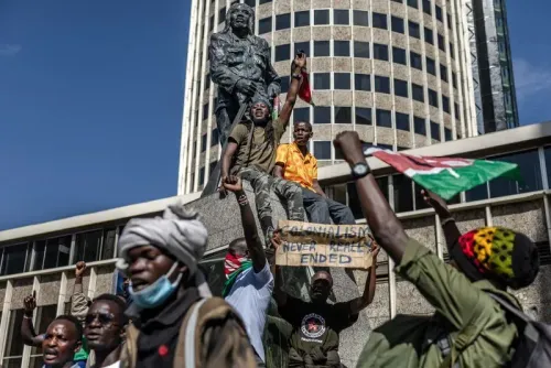 احتجاجات في نيروبي بعد وفاة المدون الكيني ألبرت أوجوانج، مع متظاهرين يحملون لافتات ويهتفون ضد الحكومة أمام تمثال.
