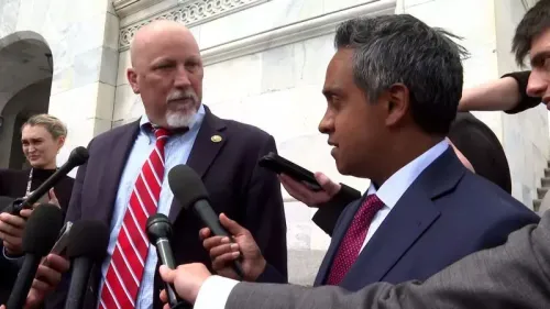 نائب في الكونغرس يتحدث مع صحفيين خارج مبنى حكومي، محاطًا بعدد من الميكروفونات، وسط أجواء توتر سياسي.