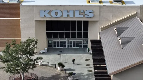 مدخل متجر كوهلز، مع شعار الشركة واضحًا، حيث يظهر شخص واحد يتجه نحو المدخل، مما يعكس التحديات التي تواجهها الشركة.