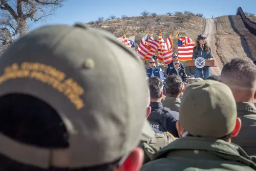 وزيرة الأمن الداخلي كريستي نويم تتحدث أمام مجموعة من الضباط، مع العلم الأمريكي في الخلفية، خلال مؤتمر حول إنفاذ قوانين الهجرة.