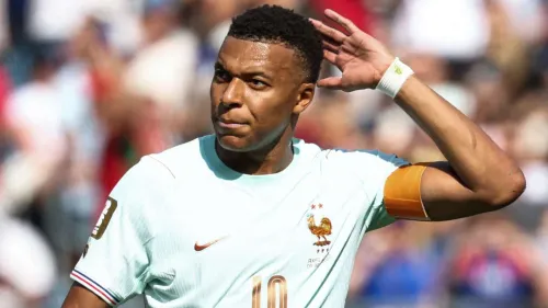 كيليان مبابي يرتدي قميص منتخب فرنسا ويرد تحية الجماهير بعد تسجيل هدف في كأس العالم 2026، مع تحديات في سباق الكرة الذهبية.