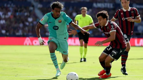لامين يامال لاعب برشلونة يراوغ مدافع ليفانتي خلال مباراة الدوري الإسباني، مع حكم المباراة في الخلفية.
