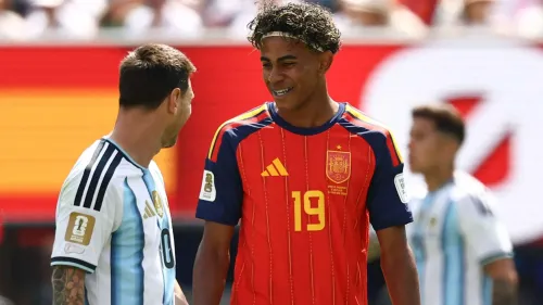لامين يامال يبتسم ويتحدث مع لاعب أرجنتيني في مباراة دولية، مع التركيز على تألقه في الدوري الإسباني ومقارنته بميسي.