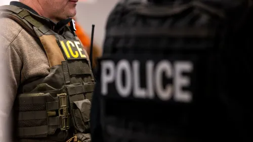 رجال إنفاذ القانون يرتدون سترات واقية تحمل علامات "ICE" و"POLICE"، في سياق تحقيقات تتعلق بالهجرة.