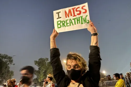 محتج في نيودلهي يحمل لافتة مكتوب عليها "أفتقد التنفس"، مع وجود حشود خلفه، في سياق أزمة تلوث الهواء.