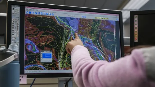 شخص يشير إلى شاشة تعرض خرائط الطقس المعقدة، تعكس التحديات التي تواجهها هيئة الأرصاد الجوية في تقديم التنبؤات الدقيقة.