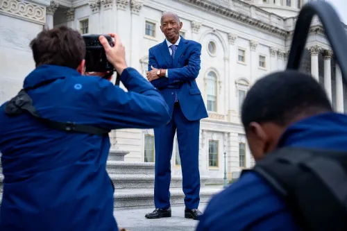 صورة لرجل يرتدي بدلة زرقاء، يقف مبتسمًا أمام مبنى حكومي، بينما يقوم مصوران بالتقاط صور له. تعكس الصورة أهمية القيادة السياسية في هيوستن.
