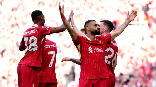 لاعبو ليفربول يحتفلون بعد تسجيل هدف في ملعب أنفيلد، مع تواجد الجماهير في المدرجات، مما يعكس أجواء الفرح والنجاح.