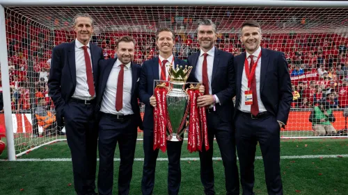 مجموعة من المسؤولين الإداريين في ليفربول يحتفلون بحمل كأس الدوري الإنجليزي الممتاز على ملعب أنفيلد، في لحظة نجاح رياضية قبل انتقال ريتشارد هيوز إلى الهلال السعودي.