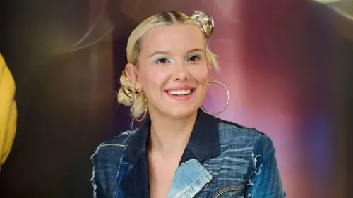 تظهر ميلي بوبي براون بابتسامة، ترتدي ملابس دنيم مع لمسات عصرية، تعكس أسلوب التسعينيات، خلال حدث في مدريد.