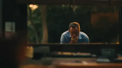 مشهد من مسلسل "اللوتس الأبيض" يظهر شخصية تيموثي، الذي يبدو قلقاً ومتوتراً، بينما ينظر من نافذة.