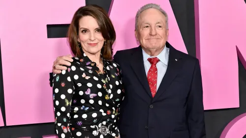 تينا فاي ولورن مايكلز يتبادلان الابتسامات في حدث، مع خلفية وردية، في إشارة إلى شراكتهم الطويلة في برنامج "SNL".