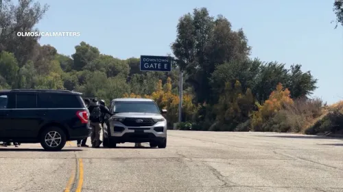 عملاء من وكالة إنفاذ قوانين الهجرة والجمارك الأمريكية يقفون عند مدخل ملعب دودجر، مع وجود سيارات في الخلفية، في سياق مداهمات الهجرة الأخيرة.