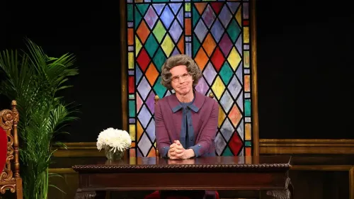 شخصية سيدة الكنيسة، تجلس خلف مكتب مع زهور بيضاء، في خلفية ملونة زجاجية، تعكس أجواء برنامج "SNL" الكوميدي.