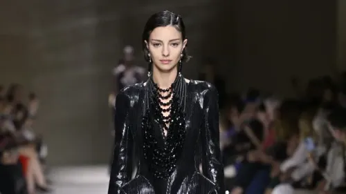 عارضة الأزياء لوسي ماركوفيتش تسير على منصة عرض أزياء، مرتدية زيًا أنيقًا مع مجوهرات بارزة، خلال حدث مميز في عالم الموضة.