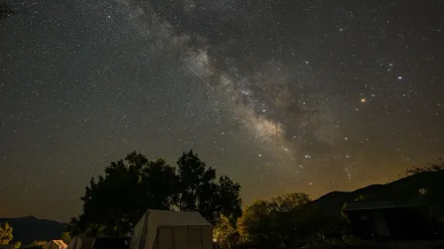 سماء مظلمة مليئة بالنجوم مع ظهور شهب الليريدات، وتظهر خطوط خافتة من الشهب في الخلفية، مما يعكس جمال الحدث السماوي.