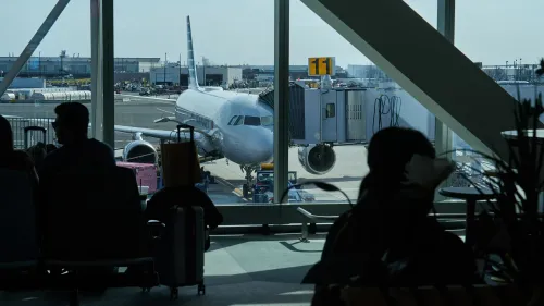 مشهد لمطار نيوارك حيث ينتظر المسافرون في صالة الانتظار، مع طائرة متوقفة عند البوابة رقم 11، وسط تأخيرات في الرحلات.