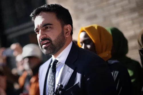 زهران ممداني يتحدث خلال تجمع حاشد في كوينز، داعماً حملته للترشح عمدة نيويورك، مع وجود مؤيدين خلفه.