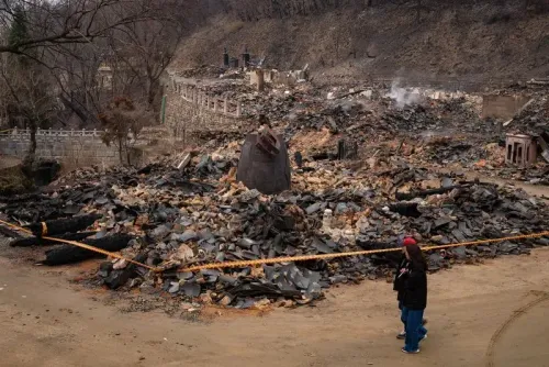 تظهر الصورة آثار حريق غابات في كوريا الجنوبية، حيث تتناثر الأنقاض حول معبد غونسا التاريخي، مع شخص يقف بجانب الحطام.