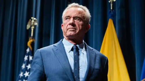 يظهر روبرت ف. كينيدي الابن، مرتديًا بدلة زرقاء، في مؤتمر صحفي، مع خلفية تضم الأعلام الأمريكية. يتناول قضايا تتعلق بالتوحد.