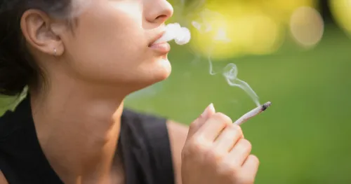 امرأة تدخن سيجارة ماريجوانا، مما يسلط الضوء على المخاطر المحتملة لاستخدامها وتأثيرها على البويضات والعقم.