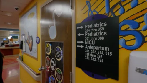 لافتة توجيهية في مستشفى، تشير إلى أقسام الأطفال والعناية المركزة، مع تفاصيل مرئية ملونة لجذب الانتباه.