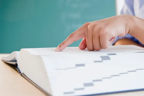 يد تشير إلى صفحة مفتوحة في قاموس، مع التركيز على تعريف كلمة "سلوب" كمحتوى رقمي منخفض الجودة.