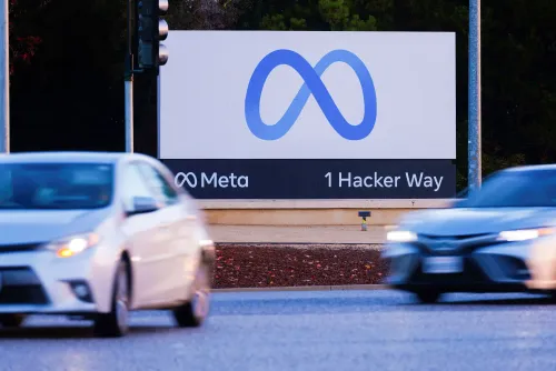 لافتة تحمل شعار "Meta" وعنوان "1 Hacker Way" على جانب الطريق، مع سيارات تمر بجوارها، تعكس التغيرات في قطاع التكنولوجيا.