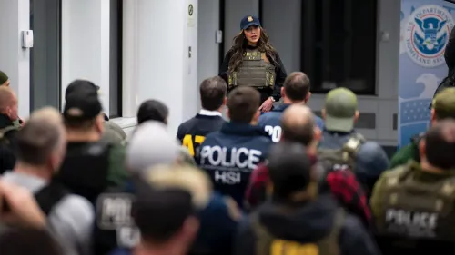 وزيرة الأمن الداخلي كريستي نويم تتحدث إلى قوات إنفاذ القانون خلال عملية لمكافحة الهجرة في نيويورك، مع ضباط يرتدون زياً رسمياً خلفها.