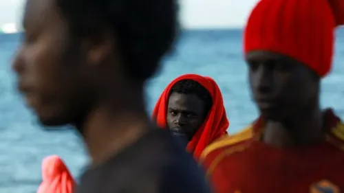 شباب مهاجرون أفارقة على شاطئ في سبتة الإسبانية، يعكسون واقع اللجوء والتحديات في ظل أزمة الهجرة شمال أفريقيا.