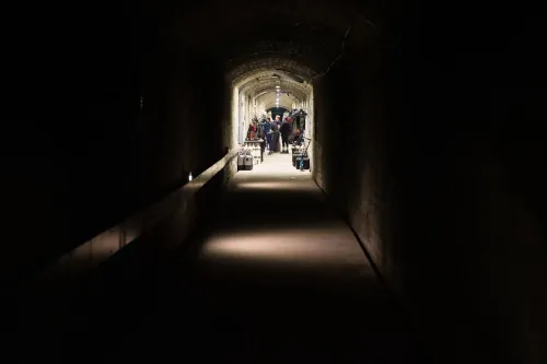 مدخل كهف مولنار يانوس في بودابست، حيث يتجمع الغواصون مع معداتهم في ممر مضاء، محاط بجدران صخرية.