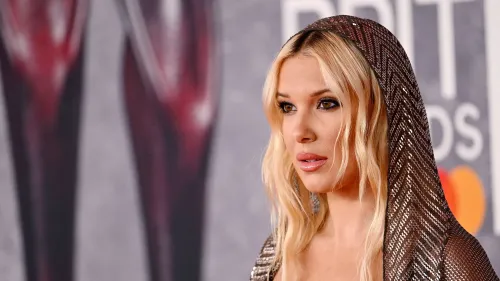 ميلي بوبي براون في حدث رسمي، ترتدي غطاء رأس لامع، وتظهر تعبيرًا مفاجئًا أثناء مناقشتها اسمها الأوسط "بوني".